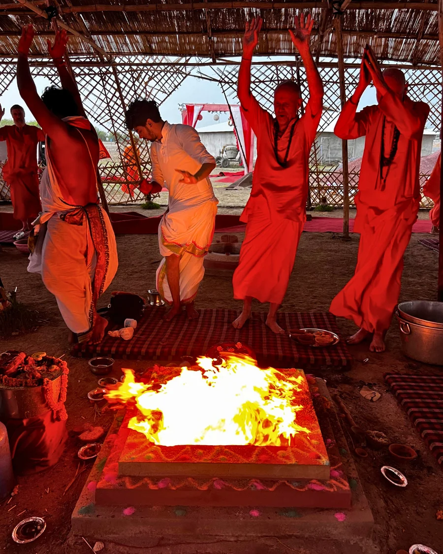 Participants with raised hands cheering at the end of the yajna at OM Ashram.